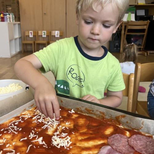 Kind beim Pizza belegen